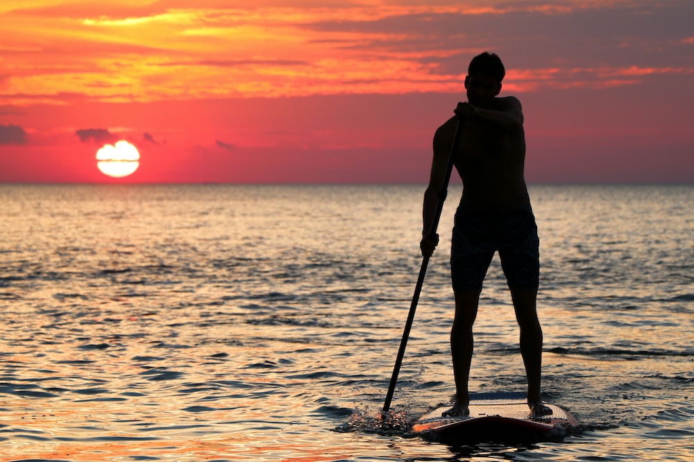 Man paddleboarding in the sunset